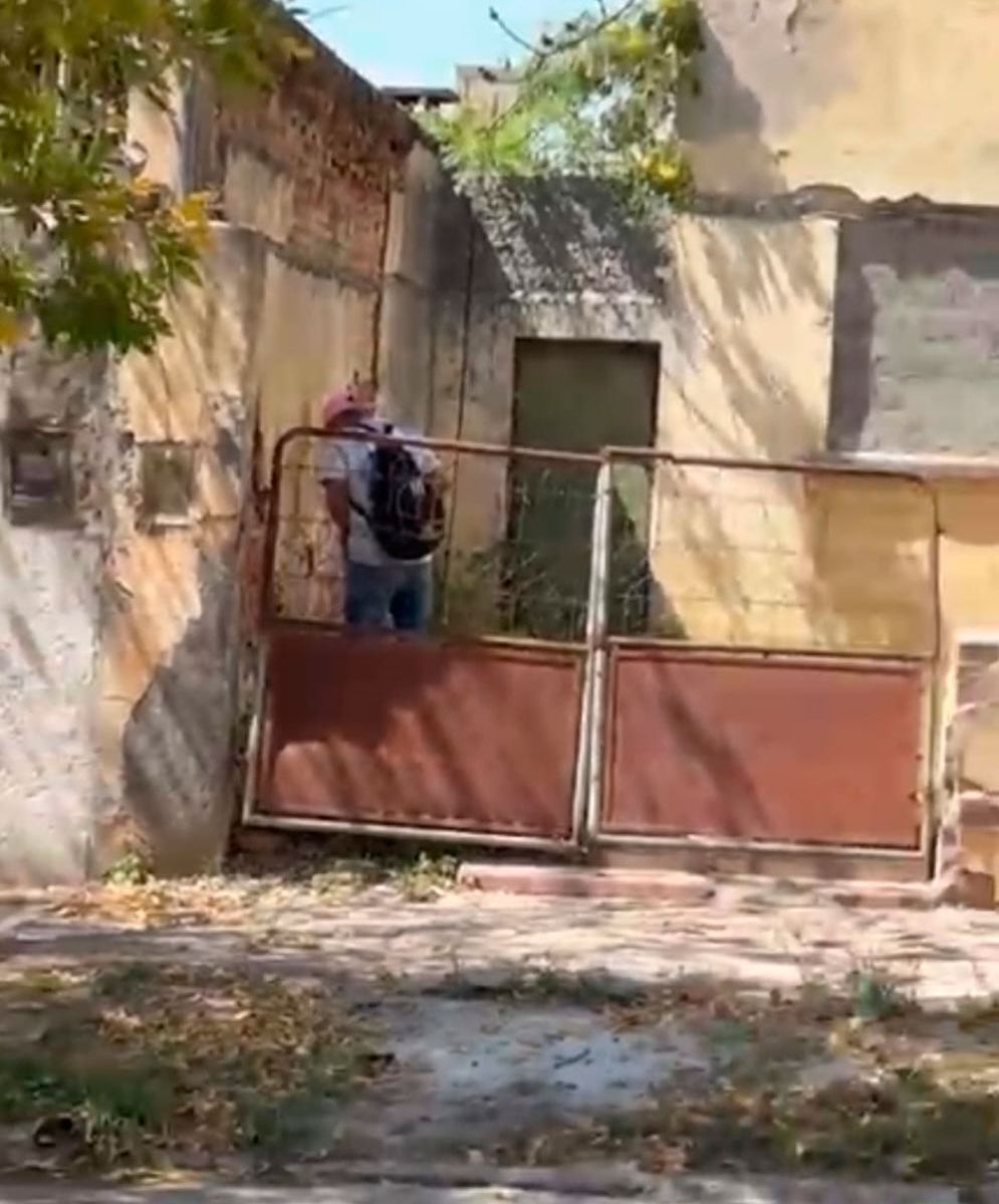 Un sujeto hace sus necesidades en el frente de una casa a plena luz del día. 